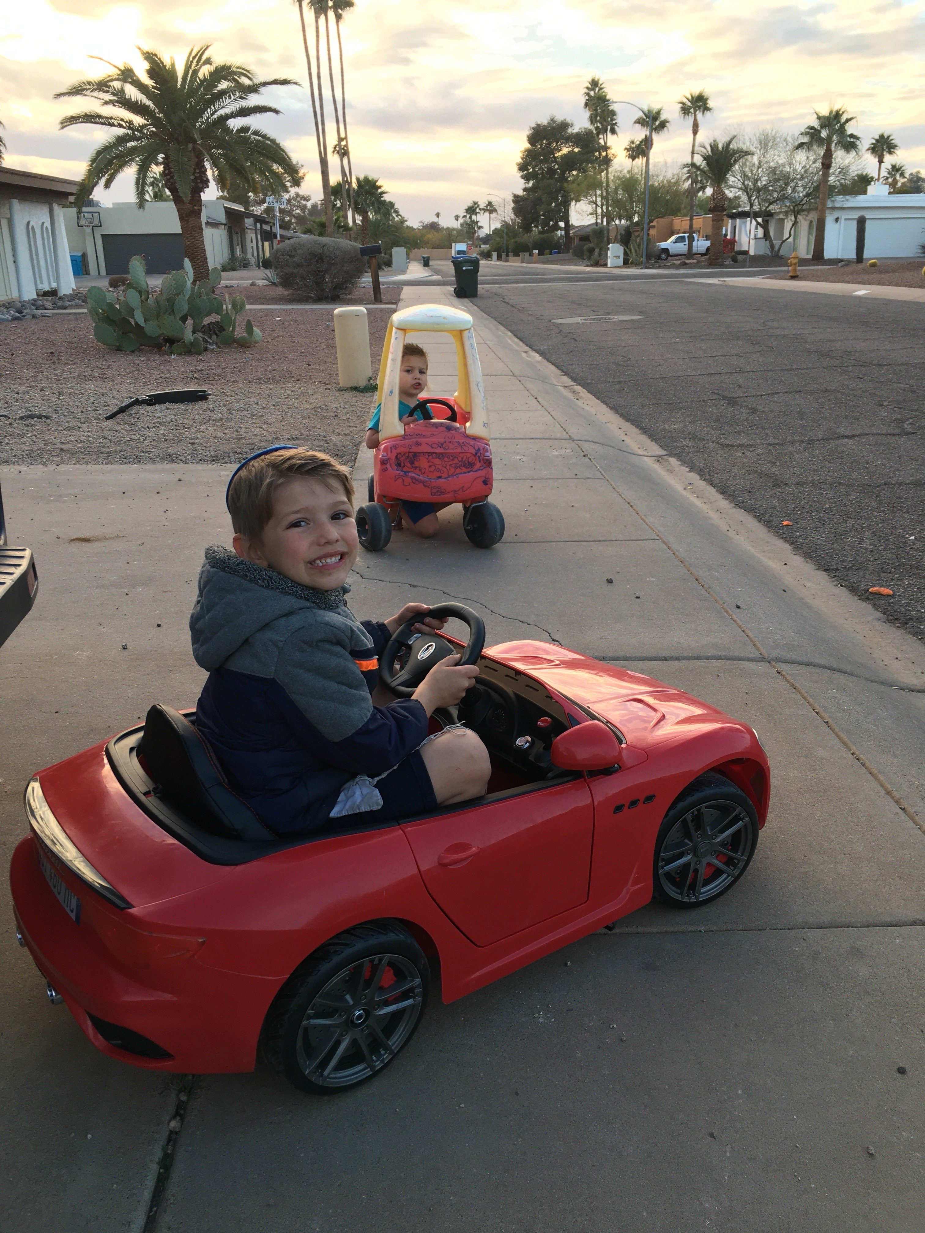 Tzivia Z's smiling son in mini car, rear side view