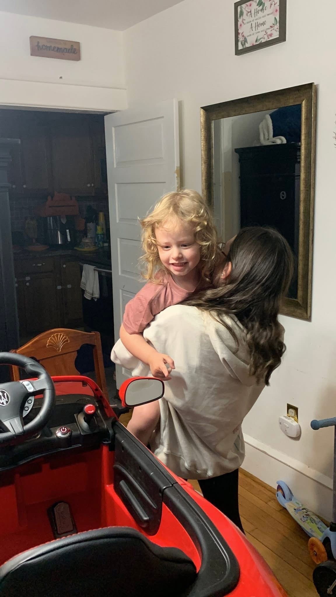 Selene Silva hugs little sister Aurora as Aurora gazes at her new red mini car with delight